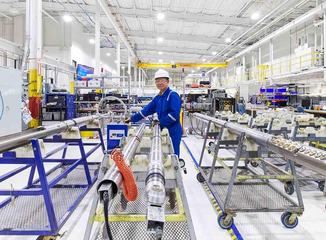 Photo of man in blue overalls working on abandonment tools in a manufacturing facility (Tier 1_ManufacturingFacility_Sugar Land_AML_5396)