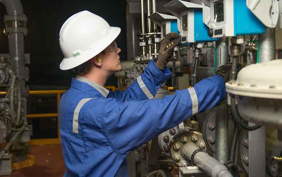 Man testing valve at 石油 treatment facility